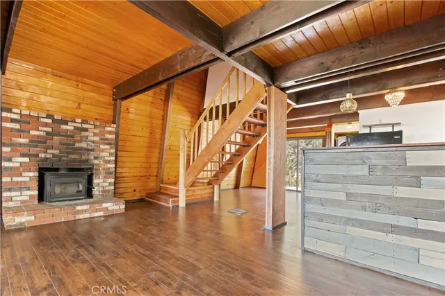 a view of an empty room with wooden floor and a fireplace