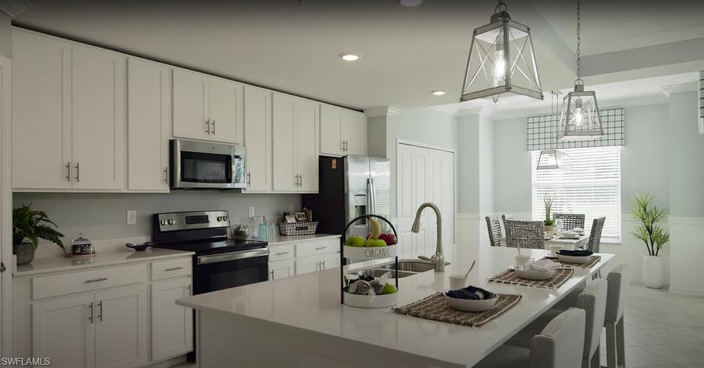 5466 Double Eagle Circle, Unit 3423 Ave Maria, FL 34142 - Photo 3 of 24 Kitchen with stainless steel appliances, sink, an island with sink, and hanging light fixtures