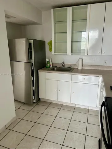a kitchen with a sink a refrigerator and cabinets