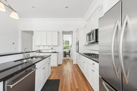 a kitchen with stainless steel appliances granite countertop a stove a sink and white cabinets