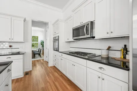 a kitchen with granite countertop white cabinets and stainless steel appliances