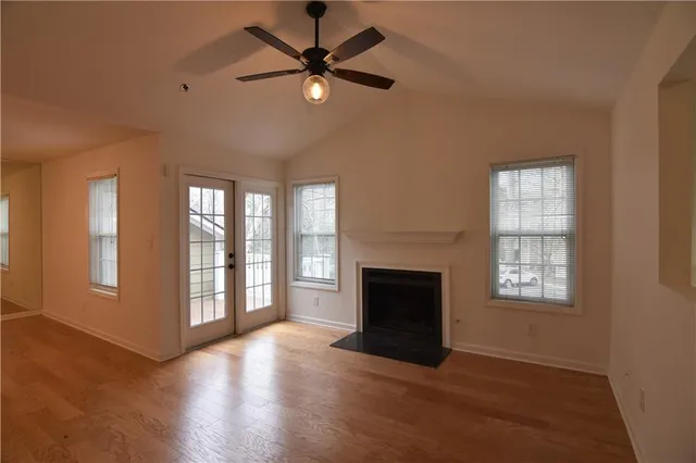 an empty room with windows and fireplace