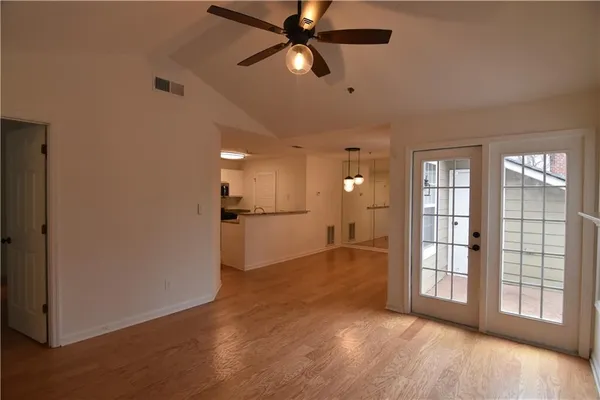 a view of empty room with wooden floor and fan