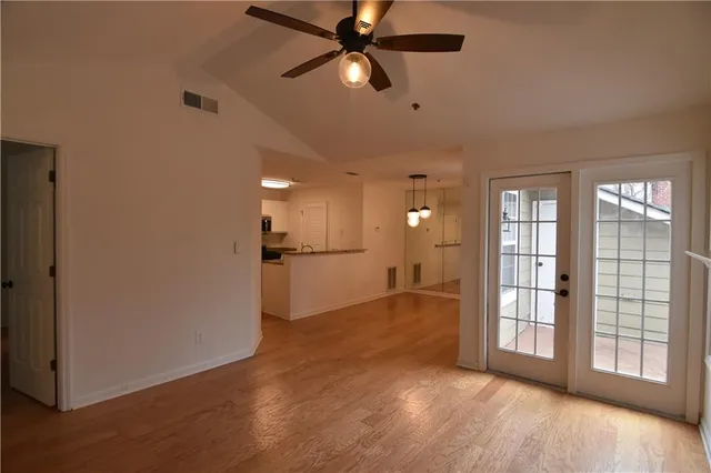 a view of empty room with wooden floor and fan