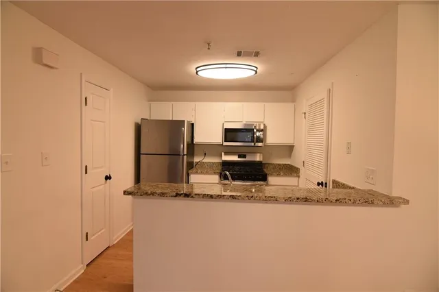 a kitchen with kitchen island granite countertop cabinets and refrigerator
