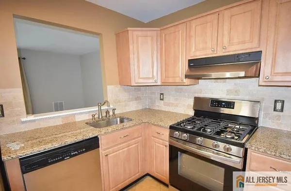 a kitchen with granite countertop a stove sink and cabinets