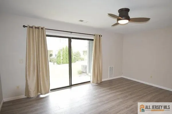 a view of empty room with wooden floor and fan