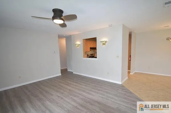 a view of an empty room with wooden floor and a ceiling fan