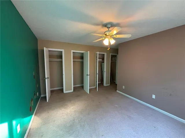 an empty room with closet and a ceiling fan