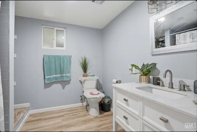 a bathroom with a granite countertop toilet a sink and a mirror