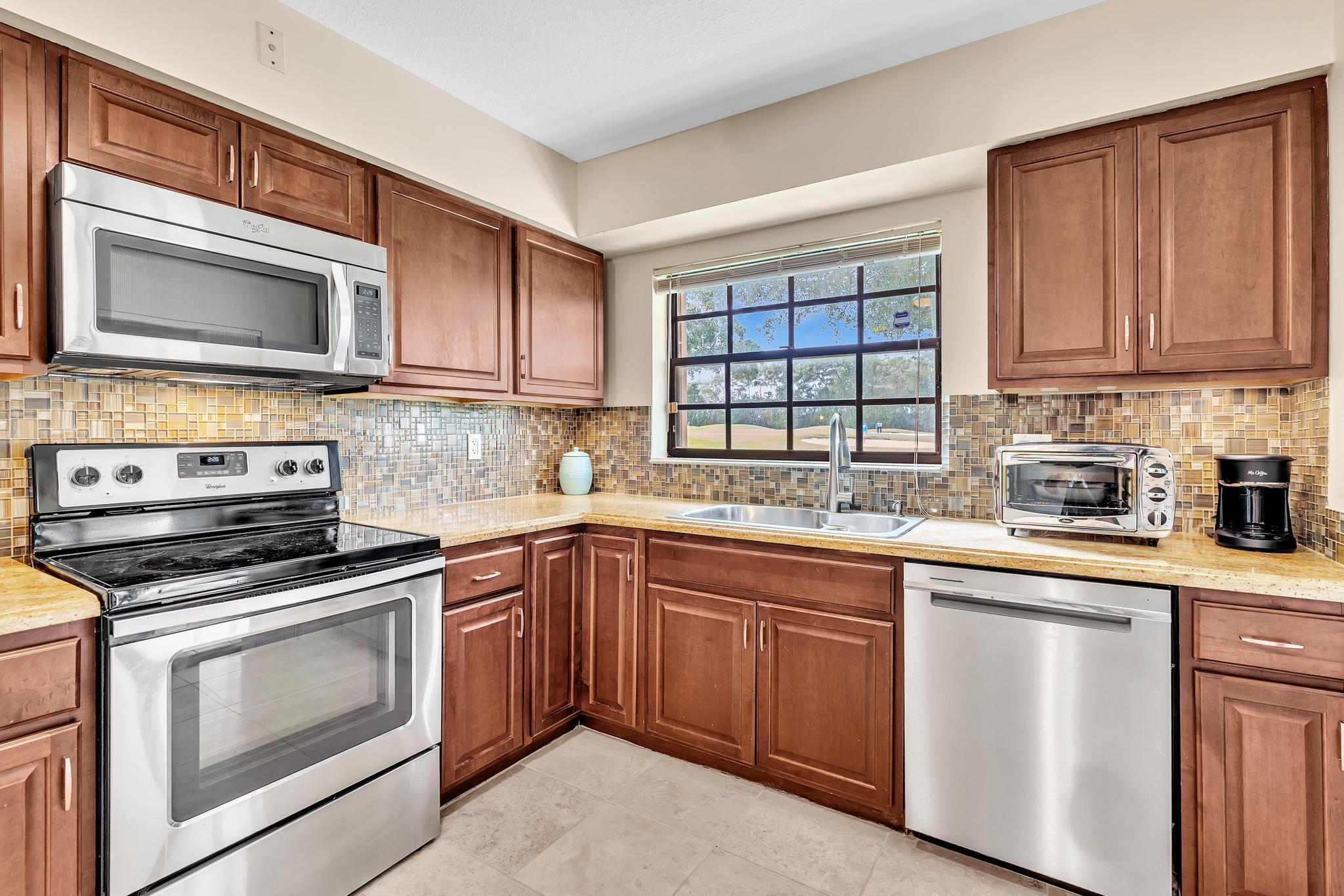 17372 Boca Club Boulevard, Unit 405 Boca Raton, FL 33487 - Photo 27 of 74 a kitchen with cabinets stainless steel appliances a sink and a window