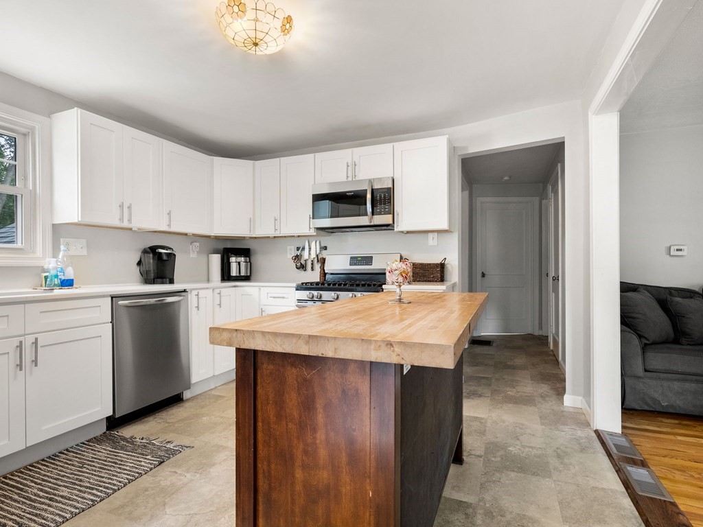 86 Anniversary Street Springfield, MA 01104 - Photo 7 of 31 a kitchen with kitchen island granite countertop a stove top oven a sink a microwave and cabinets