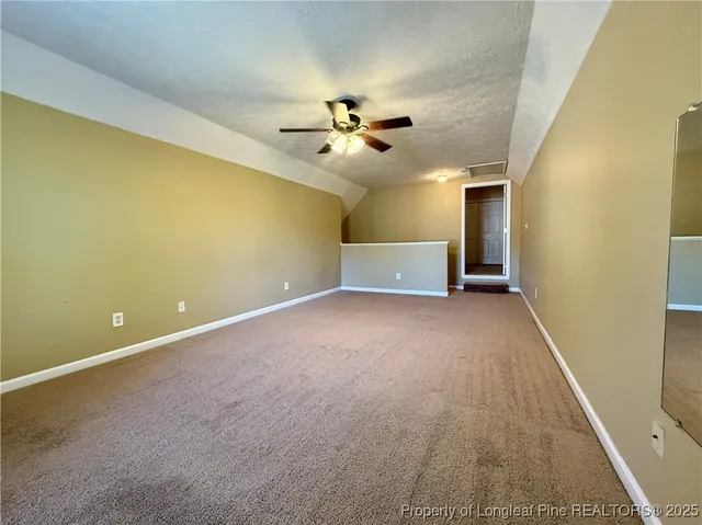 an empty room with a ceiling fan and carpet