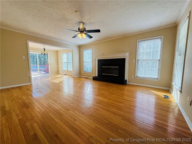 an empty room with wooden floor fireplace and windows