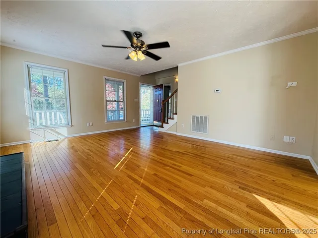 a view of an empty room with window and wooden floor
