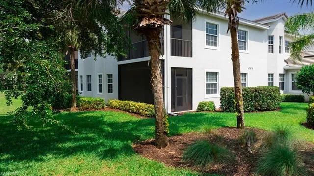 a view of a white house with a yard and large tree