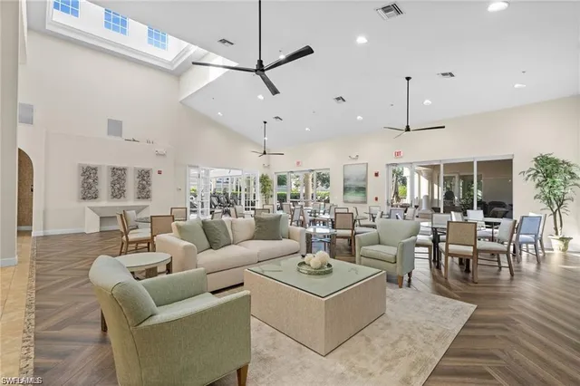 a living room with lots of furniture kitchen view and a chandelier