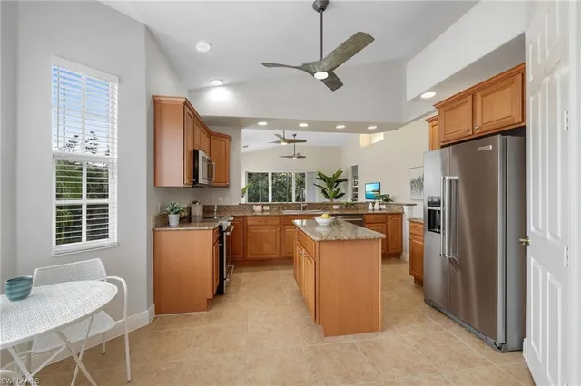 a kitchen with stainless steel appliances kitchen island granite countertop a refrigerator a stove top oven a sink dishwasher and a dining table with wooden floor