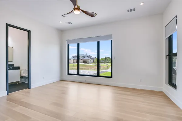 a view of an empty room with a window and wooden floor