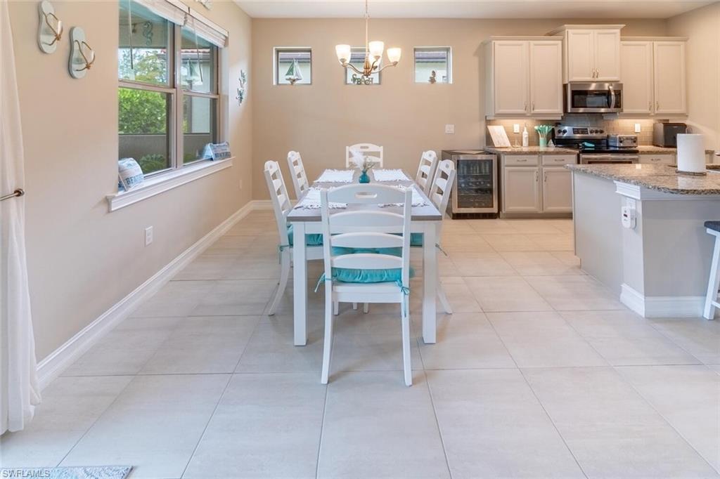 16366 Barclay Court Naples, FL 34110 - Photo 11 of 35 a kitchen with granite countertop a table chairs microwave and cabinets