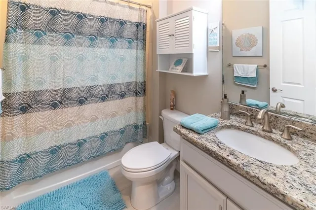 a bathroom with a granite countertop toilet sink and mirror