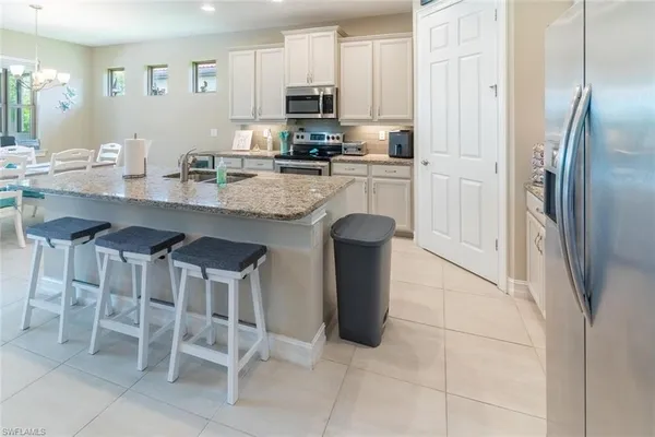 a kitchen with stainless steel appliances granite countertop a table chairs microwave and sink
