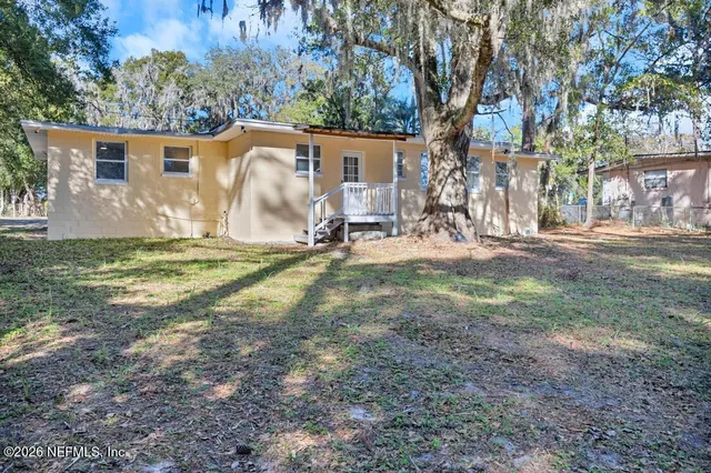 a view of a house with backyard and a tree