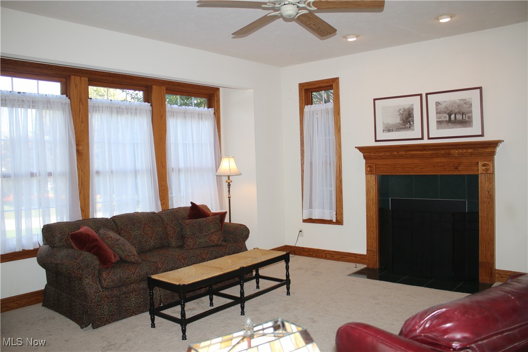 Carpeted living area featuring a tile fireplace, recessed lighting, and ceiling fan
