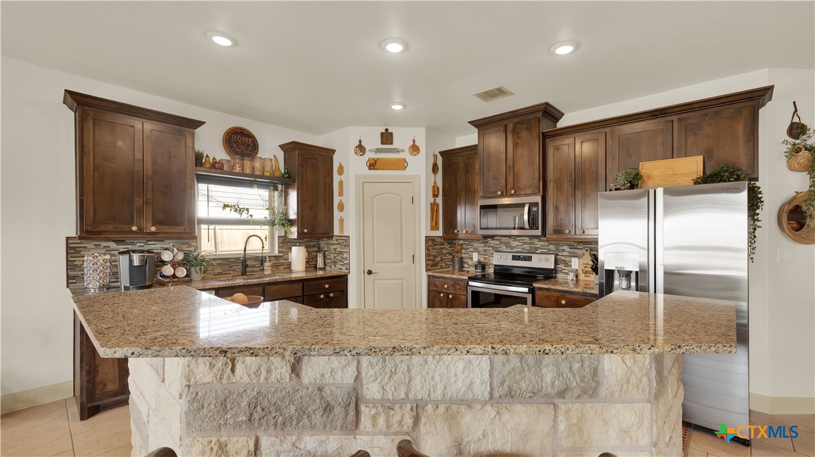 343 Meadow Valley Loop Jarrell, TX 76537 - Photo 21 of 33 a kitchen with stainless steel appliances granite countertop a refrigerator and a stove