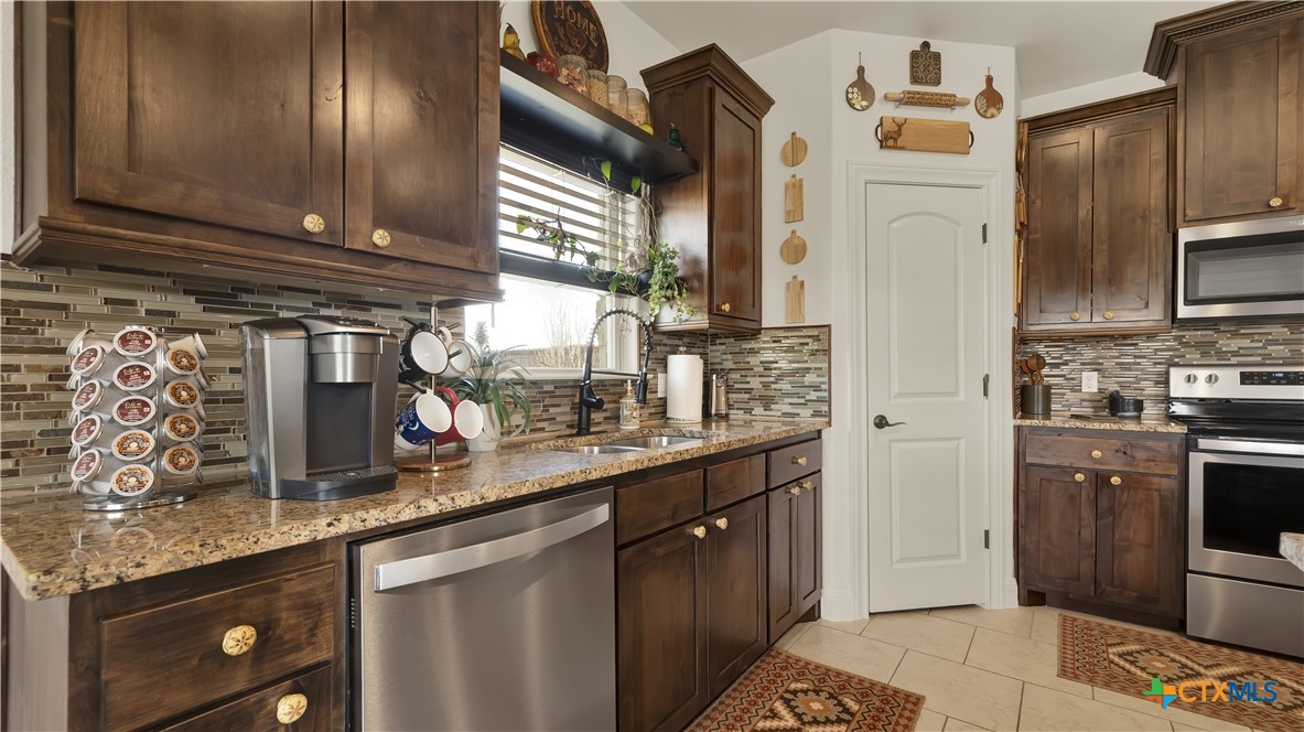 343 Meadow Valley Loop Jarrell, TX 76537 - Photo 25 of 33 a kitchen with stainless steel appliances granite countertop a sink stove and refrigerator
