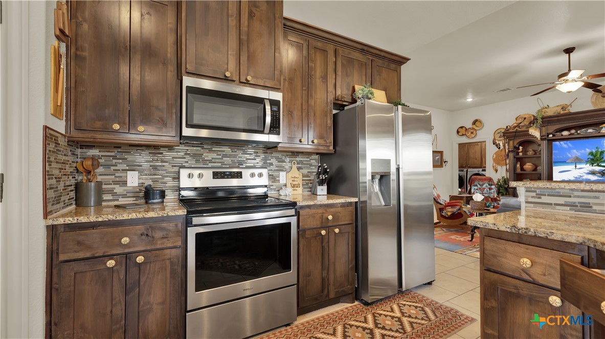 343 Meadow Valley Loop Jarrell, TX 76537 - Photo 26 of 33 a kitchen with granite countertop stainless steel appliances and wooden cabinets