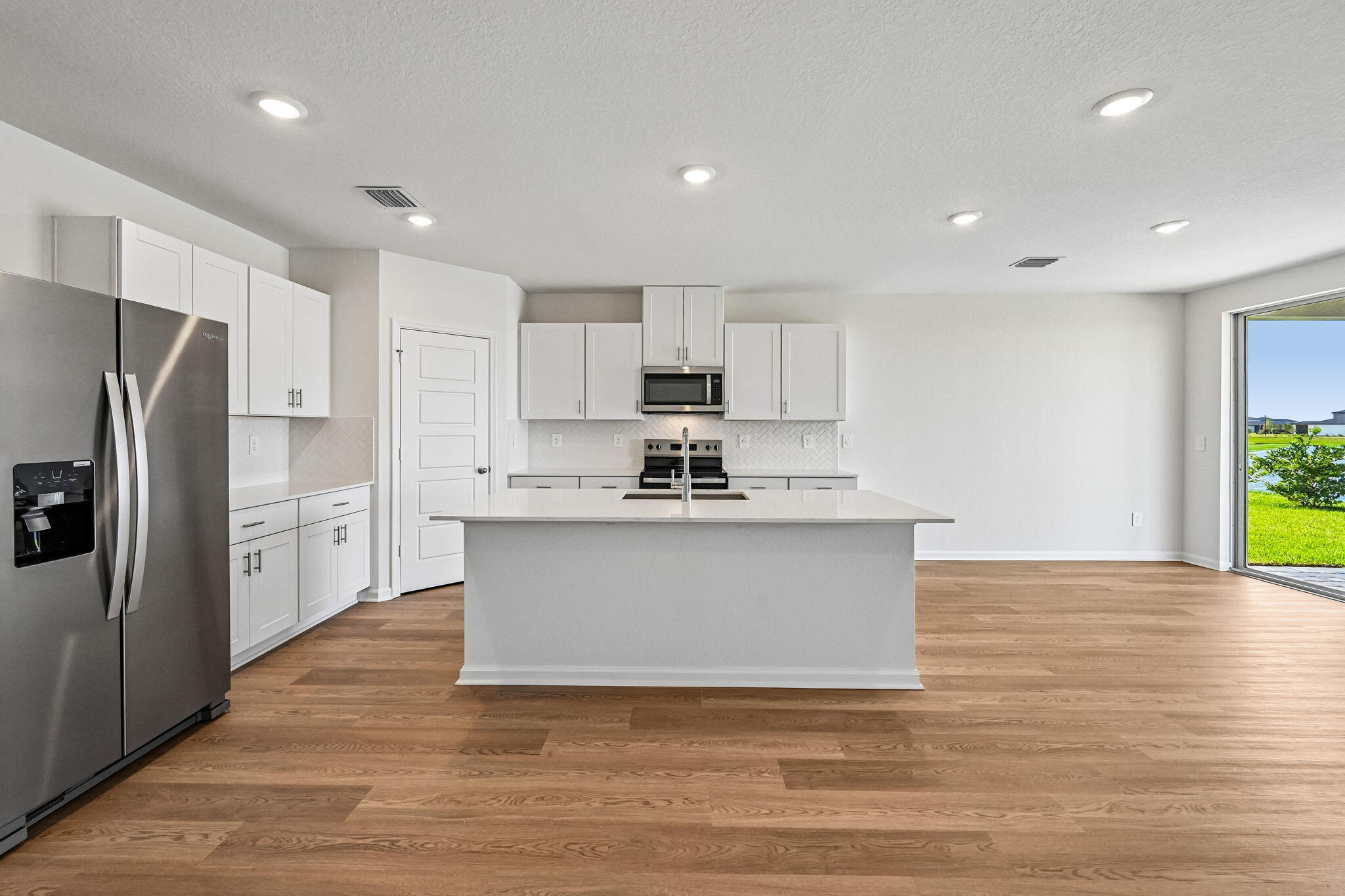14503 Southwest New Dawn Road Indiantown, FL 34956 - Photo 10 of 42 a view of kitchen with stainless steel appliances granite countertop a stove a sink a refrigerator and white cabinets with wooden floor