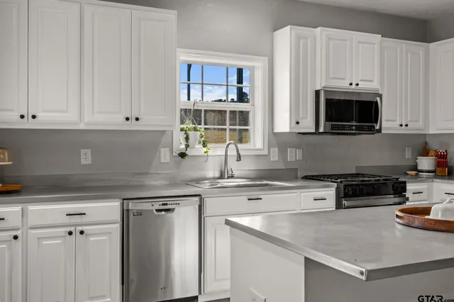 a kitchen with stainless steel appliances granite countertop a stove a sink and a microwave