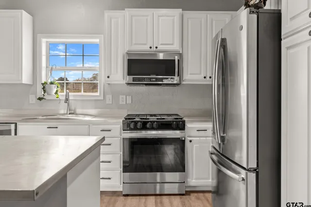 a kitchen with stainless steel appliances a stove a microwave and a sink