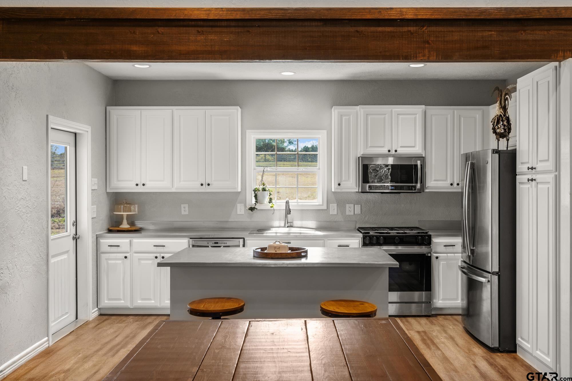 732 Red Maple Road Big Sandy, TX 75755 - Photo 29 of 40 a kitchen with stainless steel appliances granite countertop a refrigerator a stove top oven a sink dishwasher and white cabinets with wooden floor