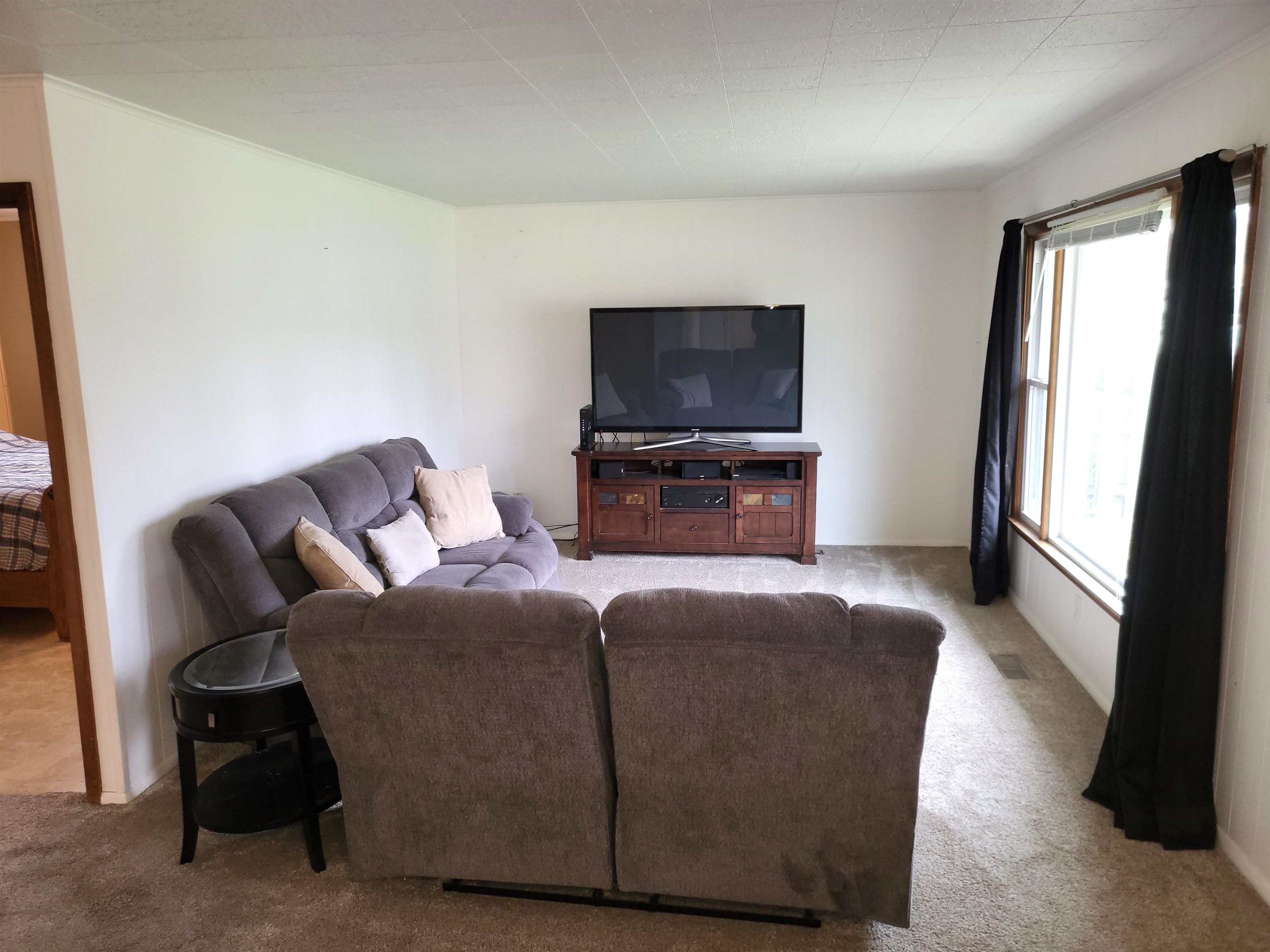 7805 Randy Road Machesney Park, IL 61115 - Photo 8 of 14 a living room with furniture a flat screen tv and a refrigerator