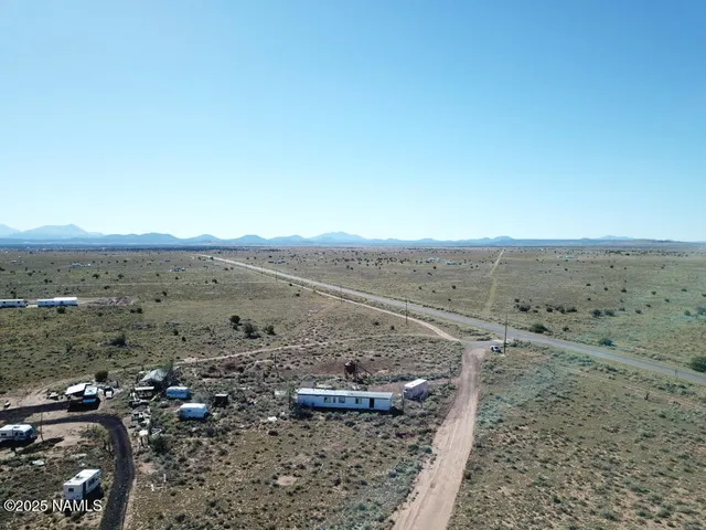 a view of a dry field with trees in background