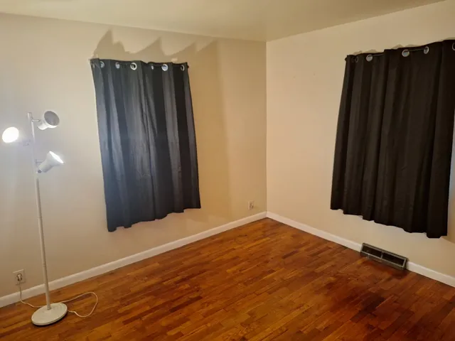 an empty room with wooden floor and mirror