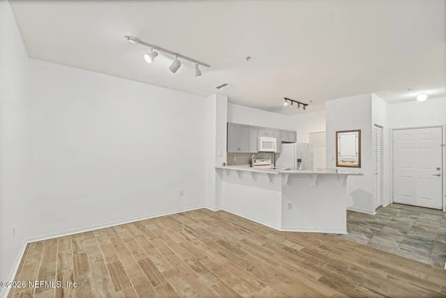 a view of a kitchen with white cabinets and wooden floor