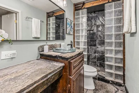a bathroom with a granite countertop sink a toilet and a mirror