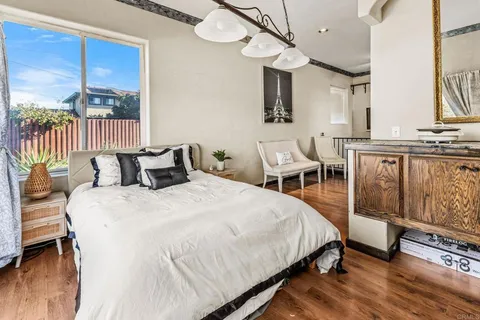 a bedroom with a bed a chandelier and flat screen tv