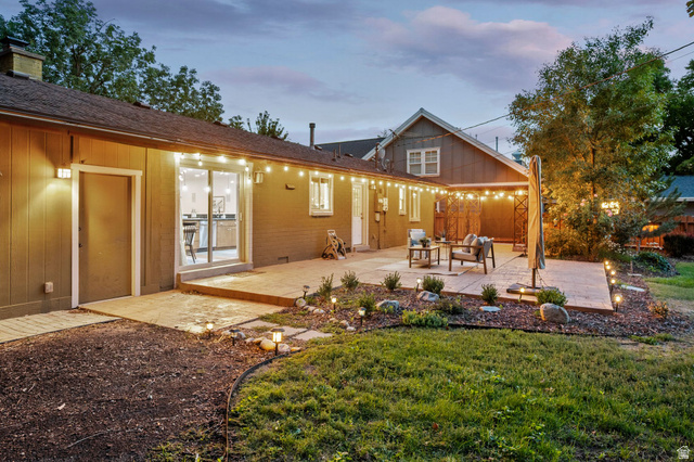 1709 Meadowmoor Road Holladay, UT 84117 - Photo 27 of 32 Expansive backyard concrete patio with integrated landscape lighting, mature trees, and a sliding glass door entry