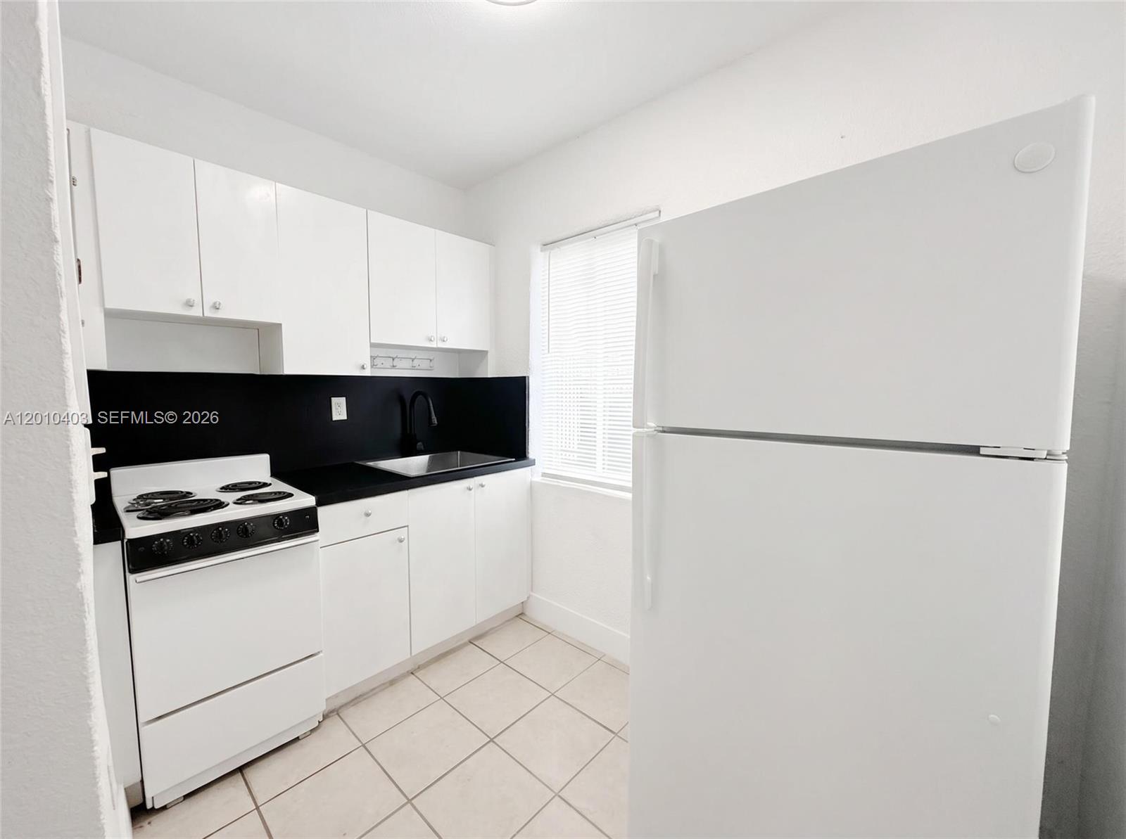 420 Northwest 10th Street, Unit 1 Miami, FL 33136 - Photo 4 of 7 a kitchen with white cabinets and white appliances