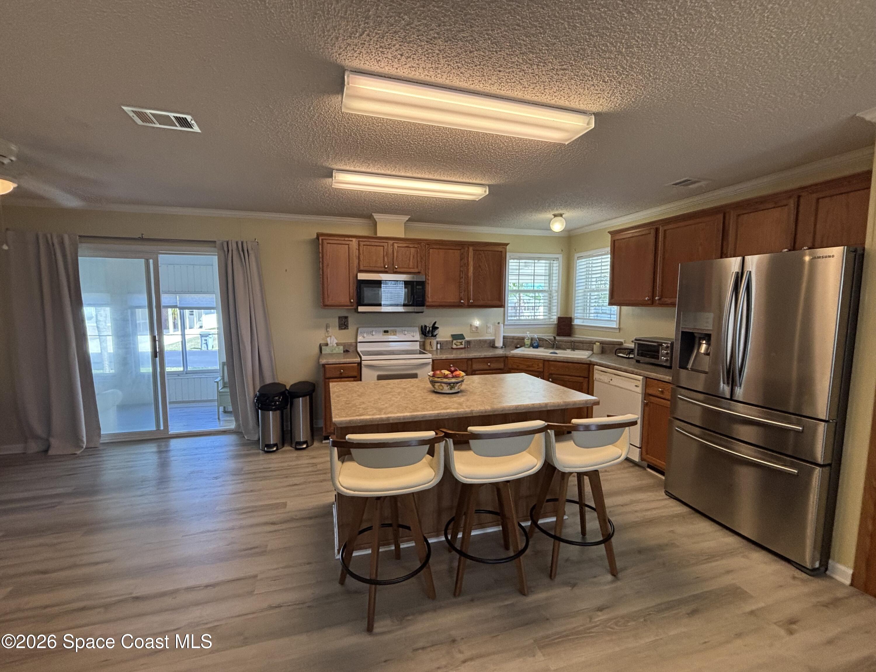 6165 98th Road Sebastian, FL 32958 - Photo 12 of 23 a kitchen with stainless steel appliances a refrigerator a stove a sink and a dining table with wooden floor
