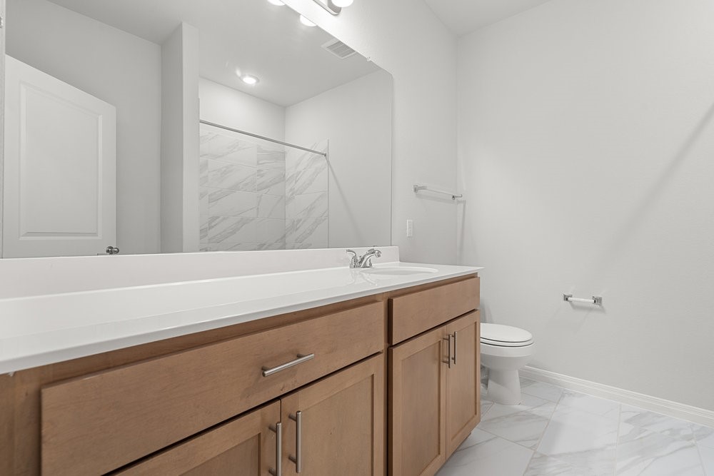 132 Condesa Street Kyle, TX 78640 - Photo 22 of 26 a bathroom with a sink a toilet and a mirror