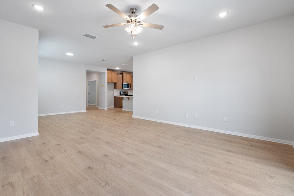 132 Condesa Street Kyle, TX 78640 - Photo 6 of 26 a view of a big room with wooden floor and a ceiling fan