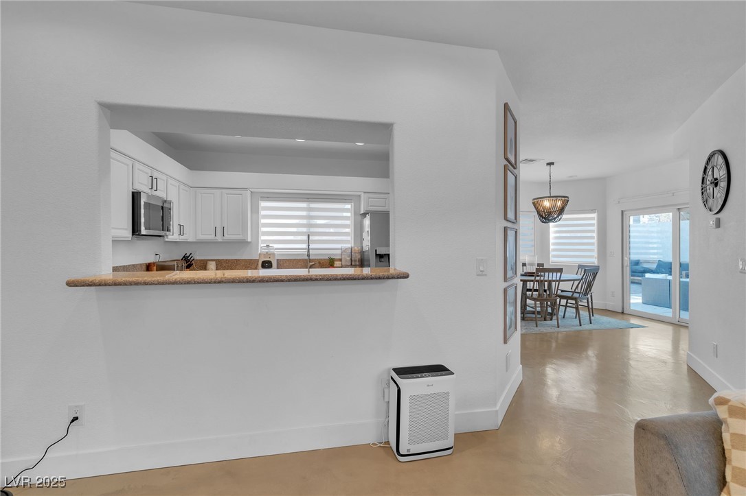 655 Florence Drive Boulder City, NV 89005 - Photo 11 of 63 Kitchen featuring white cabinetry, stainless steel appliances, concrete floors, hanging light fixtures, and light stone/granite countertops