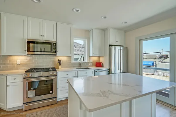 a kitchen with kitchen island a stove a sink and a refrigerator