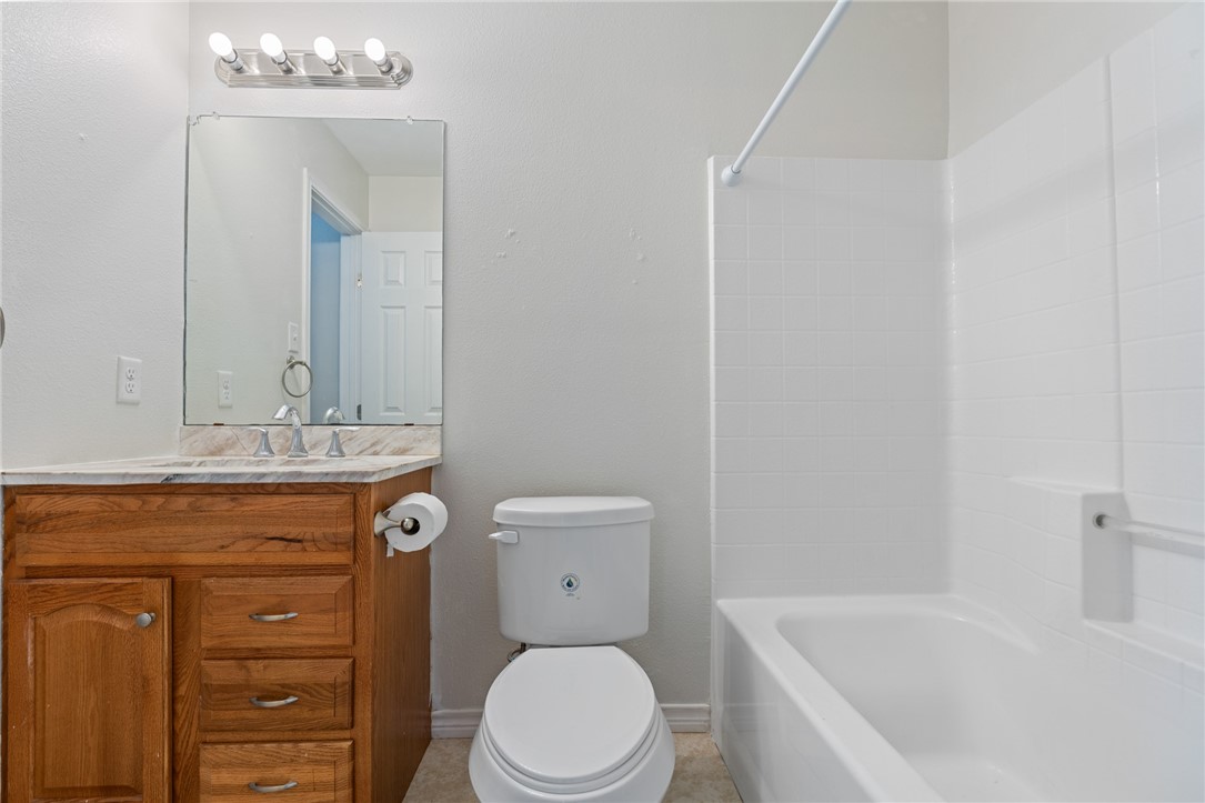 410 Knickerbocker Street Corpus Christi, TX 78418 - Photo 15 of 24 a bathroom with a granite countertop toilet a sink and a mirror