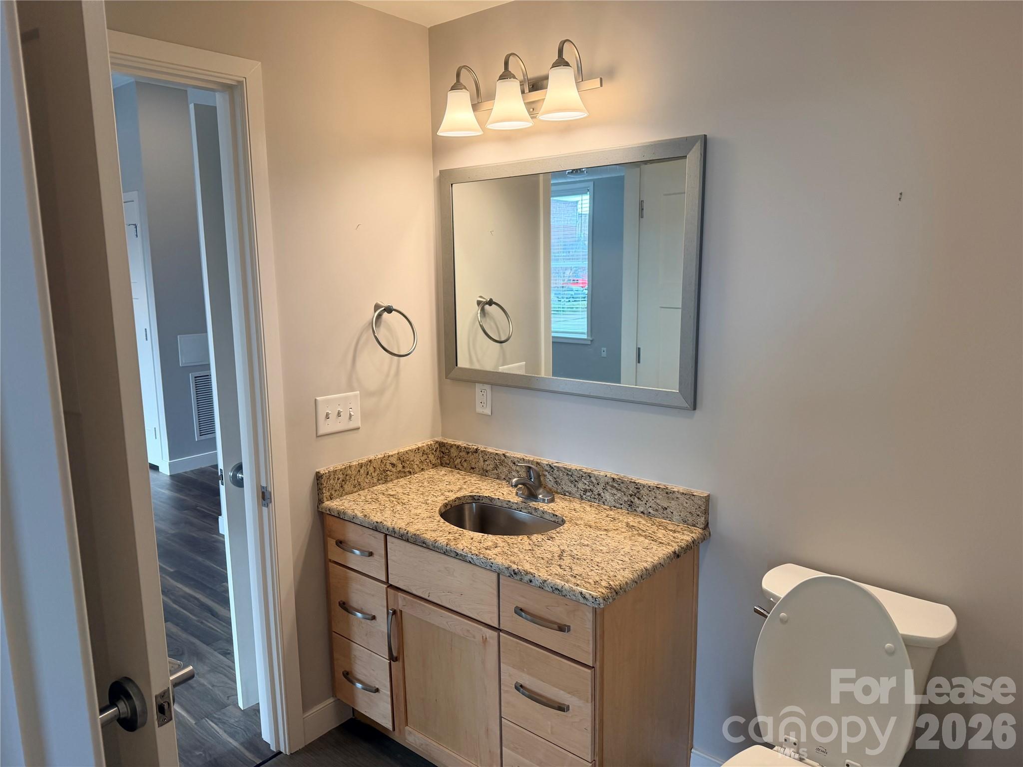 201 East Innes Street, Unit 204 Salisbury, NC 28144 - Photo 14 of 24 a bathroom with a granite countertop sink and a mirror